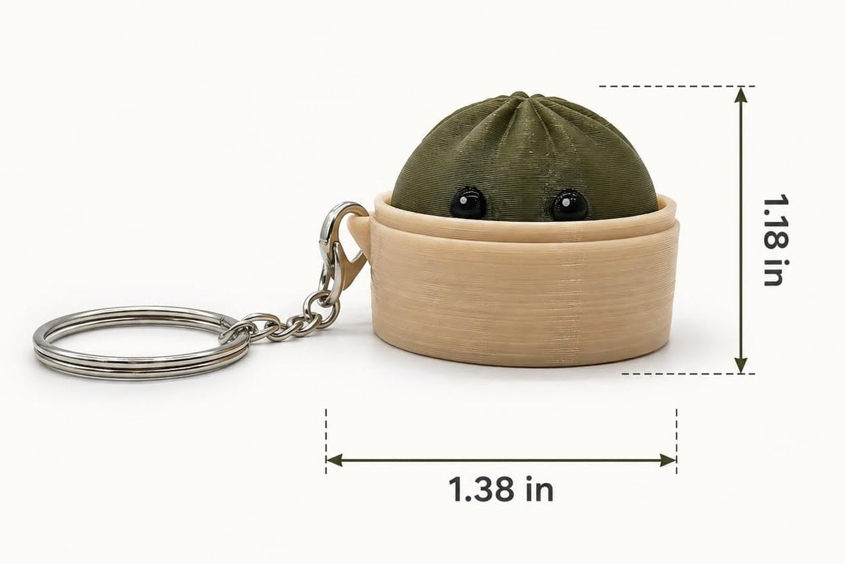 A small novelty keychain shaped like a peeking dumpling in a bamboo steamer basket, shown with measurement callouts reading 1.38 in wide and 1.18 in